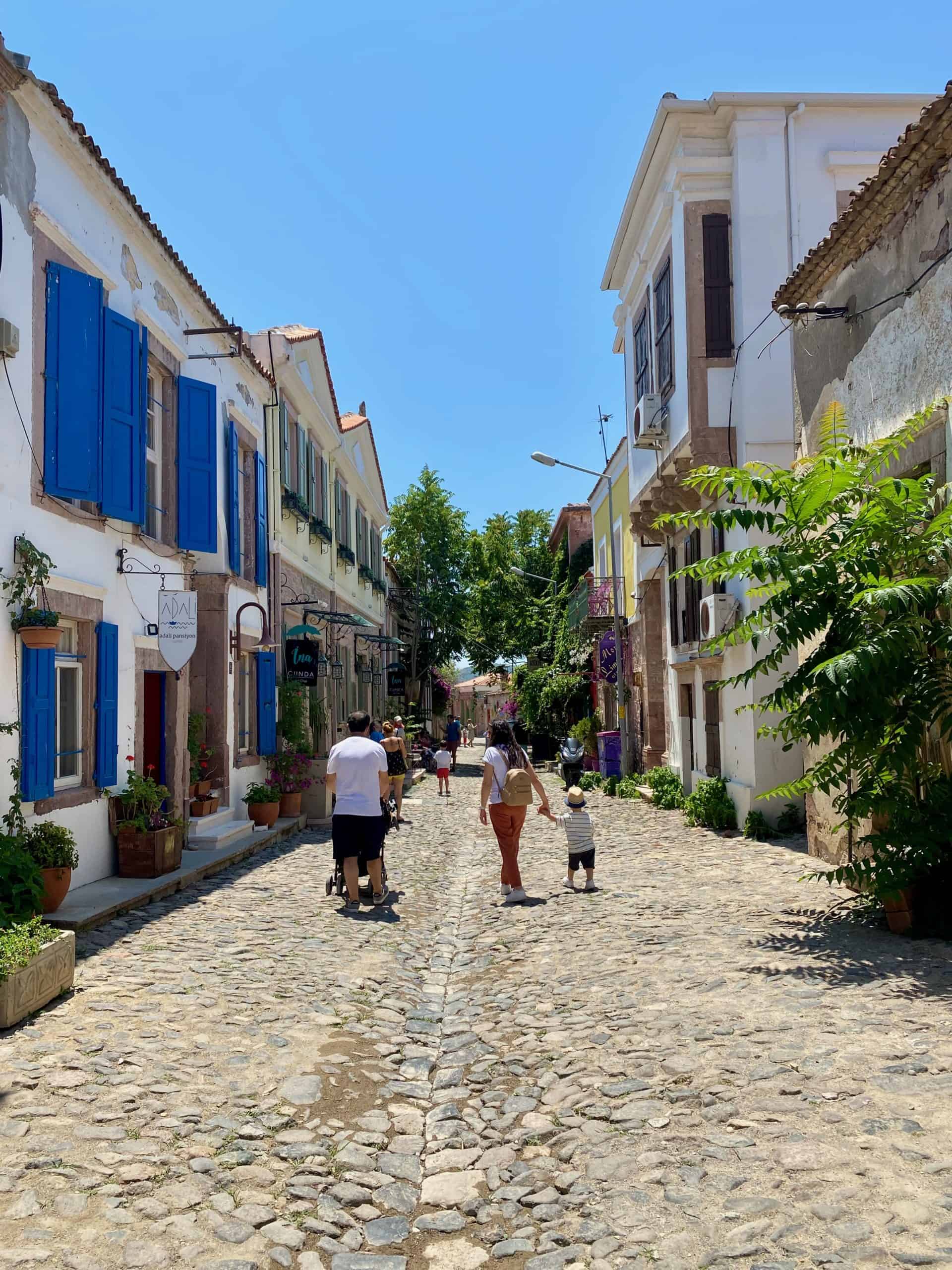 Family walking down a colorful street on Cunda Island.